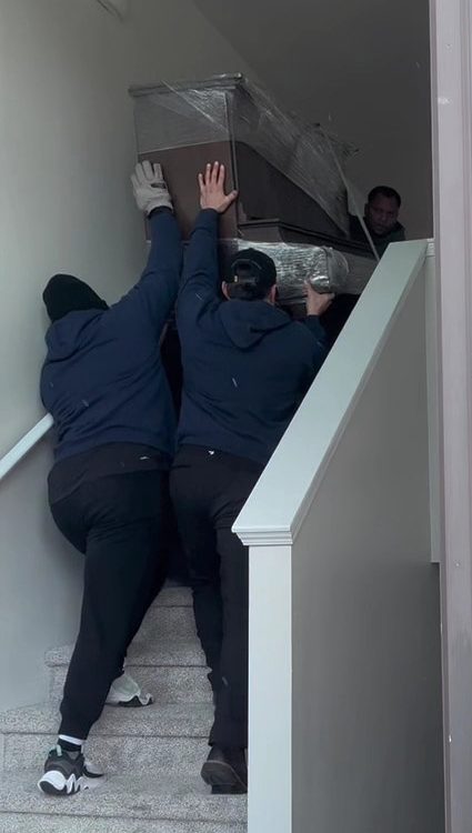 The crew easing a big wrapped piece up a staircase.